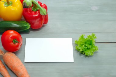 Tahta masadaki yazı için sebze ve boş kağıt.