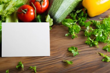 Taze sebzeler ve ahşap masada boş bir not..
