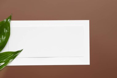 Masanın üzerinde yeşil bir yaprak olan beyaz bir sayfa..