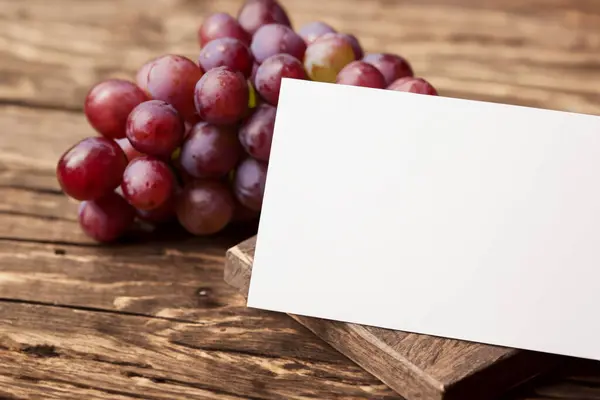 stock image fresh grapes with blank sheet for text on wooden background