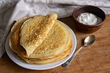 Pancake. Pancakes stack with sour cream, traditional Russian pancakes - blini on wooden background clipart