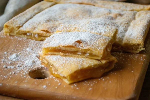Delicious covered lemon pie with powdered sugar on a wooden kitchen board