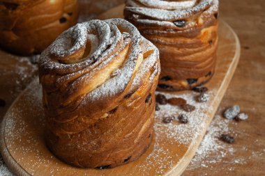 Mutlu Paskalyalar. Geleneksel Paskalya pastaları, ev yapımı kuru üzümlü kraffinler, şekerli meyveler. Seçici odaklanma. Ev yapımı Cruffin 'e yakın çekim. Ahşap arkaplan.