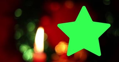 Büyük yeşil yıldız çerçeveli Mutlu Noeller. Güzel titreyen mum ve kırmızı arkaplan üzerindeki bokeh etkisi.