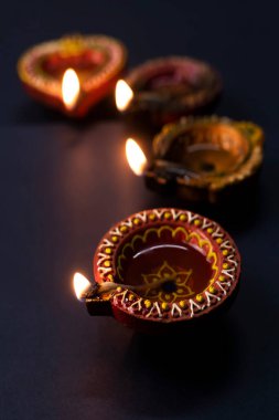 Mutlu Diwali 'ler, Diya lambaları Diwali kutlaması sırasında siyah arka planda yanıyor. Hindu Işık Festivali.