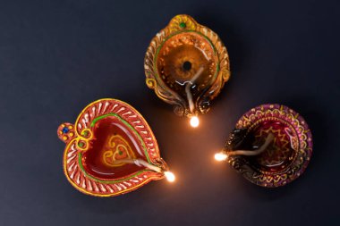 Mutlu bayramlar. Diwali kutlamaları sırasında siyah arka planda renkli kil diya lambaları yandı.