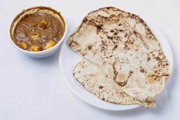 Indian traditional food, chapati or naan roti with paneer butter masala curry in a bowl on white background. close-up