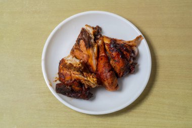 Tahta masada beyaz tabakta ızgara tavuk..