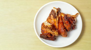 Beyaz tabakta kızarmış tavuk, ahşap masada..