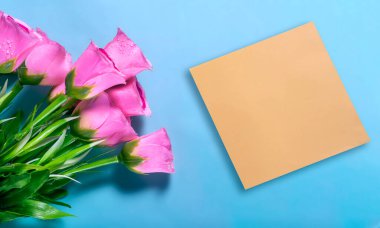 Mavi arka planda sarı bir kart olan pembe güller.