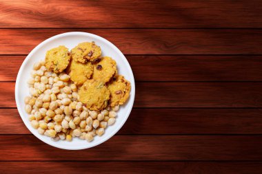 Ahşap bir arka planda masala vada 'lı haşlanmış nohut.