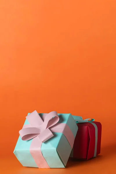 Colorful gift boxes with pink ribbon on orange background with copy space for your text