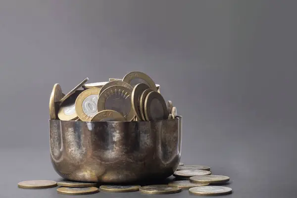 Indian ten rupee coins in a copper bowl on a gray background with copy space