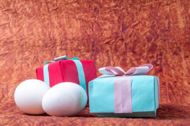 Kahverengi kağıdın üzerinde hediye kutuları ve beyaz paskalya yumurtaları. Mutlu Paskalyalar.