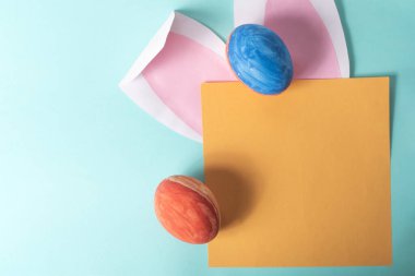 Paskalya yumurtaları ve mavi arkaplanda yazı için yeri olan boş bir kağıt kart. Asgari konsept, Üst Görünüm.