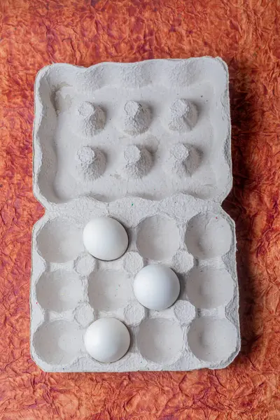 White eggs in a carton box on a textured background. Top view.
