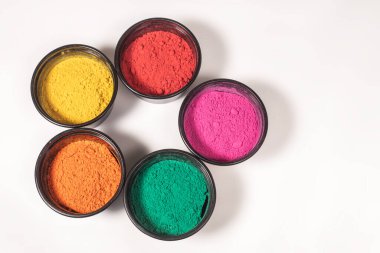 Beyaz arka planda izole edilmiş kasedeki renkli geleneksel holi tozunun üst görüntüsü. Üst görünüm