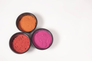 Beyaz arka planda plastik kutuda çok renkli Holi tozu. Hint Holi Festivali