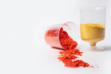 Fotokopi alanı olan beyaz bir arkaplan üzerindeki ölçüm bardaklarında renkli holi tozu