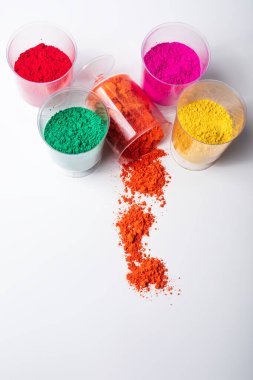 Plastik bardaklardaki renkli holi tozunun beyaz arka planda fotokopi alanı ile dikey çekimi. en üstteki görünüm