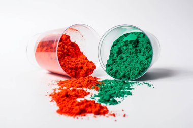 Beyaz arka planda izole edilmiş cam bir kabın içindeki renkli holi tozu. Holi festivali.