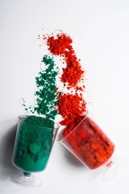 Beyaz arka planda izole edilmiş cam bir kabın içindeki renkli holi tozu. Holi festivali.