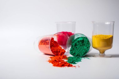 Beyaz zemin üzerinde izole edilmiş cam bir kapta bulunan renkli holi tozu. Holi festivali.