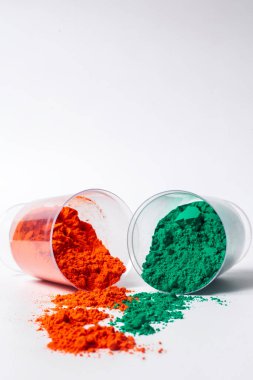 Cam bir kapta beyaz arka plana yaslanmış renkli holi tozu. seçici odak