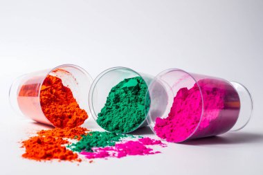Beyaz arka planda izole edilmiş cam bir kabın içindeki renkli holi tozu. Holi festivali.