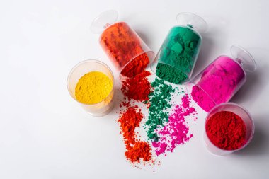 Beyaz arka planda izole edilmiş cam bir kabın içindeki renkli holi tozu. Holi festivali.
