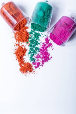 Beyaz arka planda plastik kaplarda üç renkli Holi tozu. Üst görünüm.
