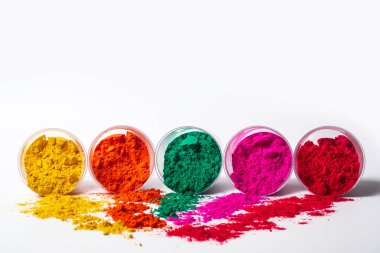 Beyaz arka planda izole edilmiş cam bir kabın içindeki renkli holi tozu. Holi festivali.