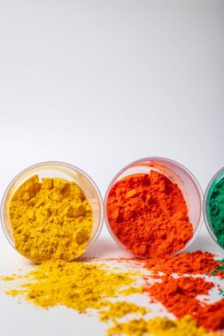 Beyaz arka planda plastik bir kapta renkli holi tozu. Holi, Hint renk festivali.