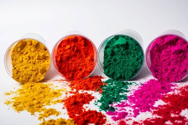 Beyaz arka planda plastik bir kapta renkli holi tozu. Holi, Hint renk festivali.