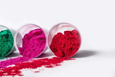 Beyaz arka planda plastik bir kapta renkli holi tozu. Holi, Hint renk festivali.