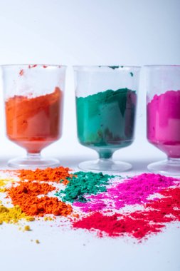 Beyaz arka planda izole edilmiş bardaktaki renkli holi tozu. Hint festivali Holi