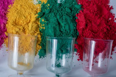 Beyaz zemin üzerinde boş cam vazo olan renkli holi tozu. Hint Holi festivali konsepti