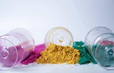Pembe, yeşil, sarı üç farklı renk holi tozu ve beyaz arka planda cam kavanozlar. Holi festivali