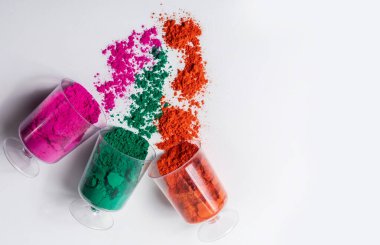 Beyaz arka planda plastik bir kapta renkli holi tozu. Üst görünüm