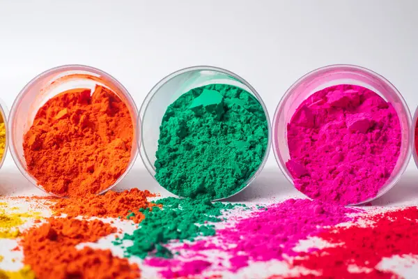 Beyaz arka planda plastik bir kapta renkli holi tozu. Holi, Hint renk festivali.