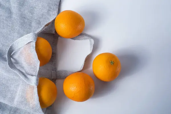 新鲜成熟的橙子放在白色背景的可重复使用购物袋中 顶部视图 复制空间 图库图片