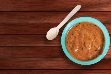 Masasında tahta kaşıkla mavi bir kasede soğan turşusu. Üst görünüm.