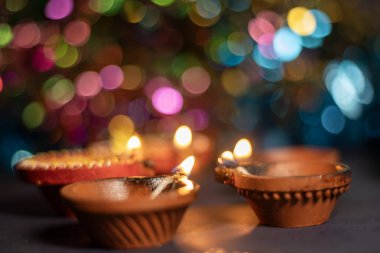 Diwali diya 'ya yakın ya da renkli bokeh arkaplanı üzerine lamba yakın. Seçici odak