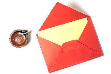 Beyaz arka planda geleneksel yanan kil yağ lambası için boş notla dolu canlı kırmızı bir zarf..