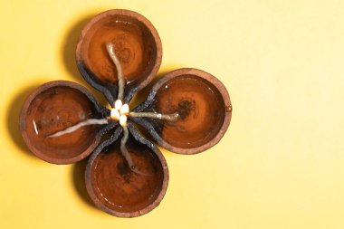 Diwali Celebration - Diya oil lamps are arranged in a beautiful floral pattern on a vibrant yellow background during the Hindu festival celebration. clipart