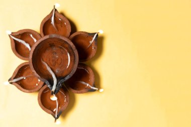 Geleneksel kil diya lambaları Diwali festivali kutlamaları sırasında sarı arka planda çiçek deseninde yakılır. Metin için alanı kopyala.