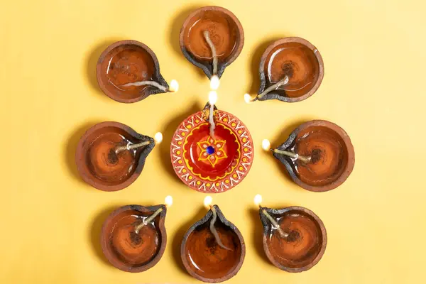 stock image Traditional clay diya lamps lit in flower pattern on yellow background in Diwali celebration. It is used during Diwali, Karthigai Deepam and other Indian festivals.