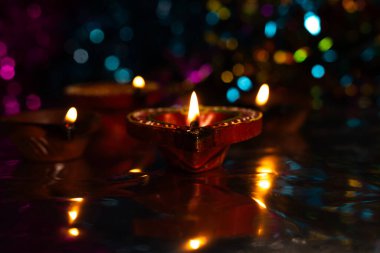 Koyu arkaplanda bokeh etkisi olan güzel ışık yansıması ile parlayan Diwali diyas. Seçici odak.