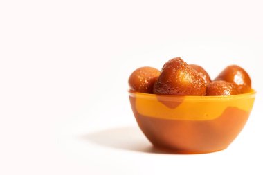 Geleneksel Hint lezzeti Gulab Jamun tatlıları beyaz arka planda canlı turuncu bir kasede servis edilir. Metnin için boşluk kopyala