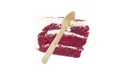 Beyaz arka planda, üzerinde tahta bir kaşık olan lezzetli bir kırmızı kadife pasta..